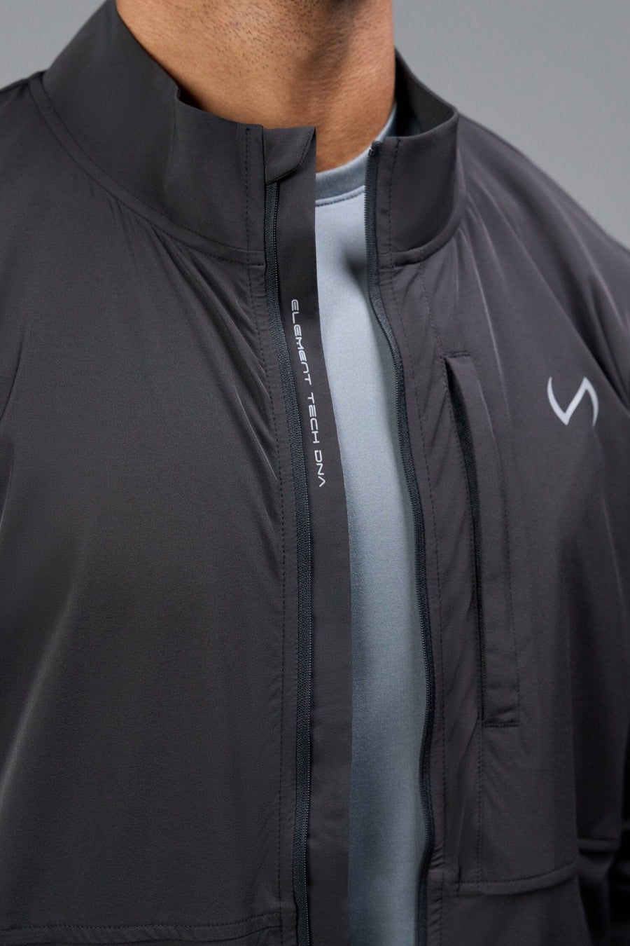 Detail Front View of Black TLF Element Athletic Jacket, featuring multiple zipper pockets, and ripstop panels for breathability and stretch