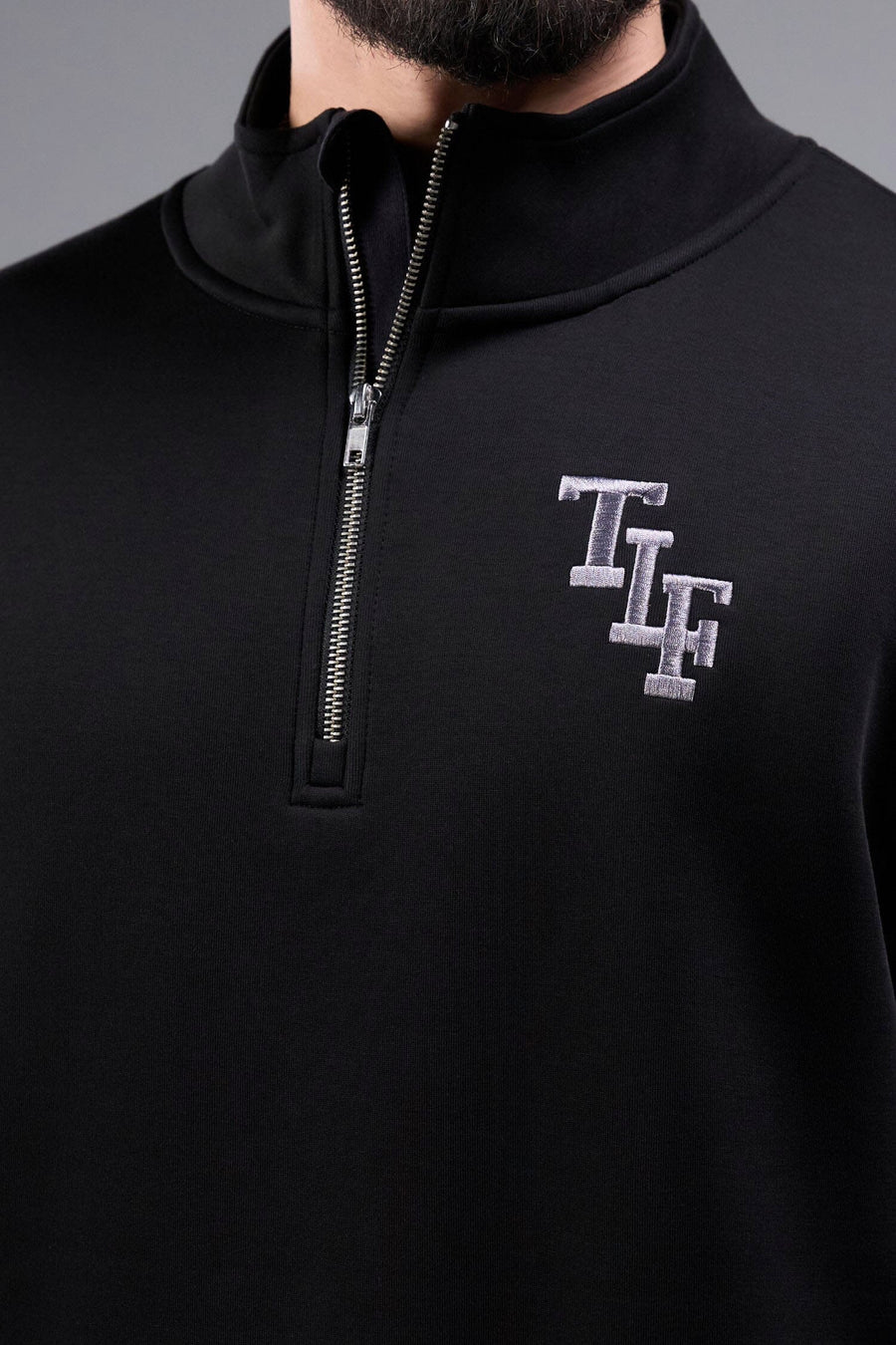 Detail Front View of Black TLF GTS Scuba Tech Quarter-Zip Pullover, featuring a ¼ zip pullover, sleek design and kangaroo pockets