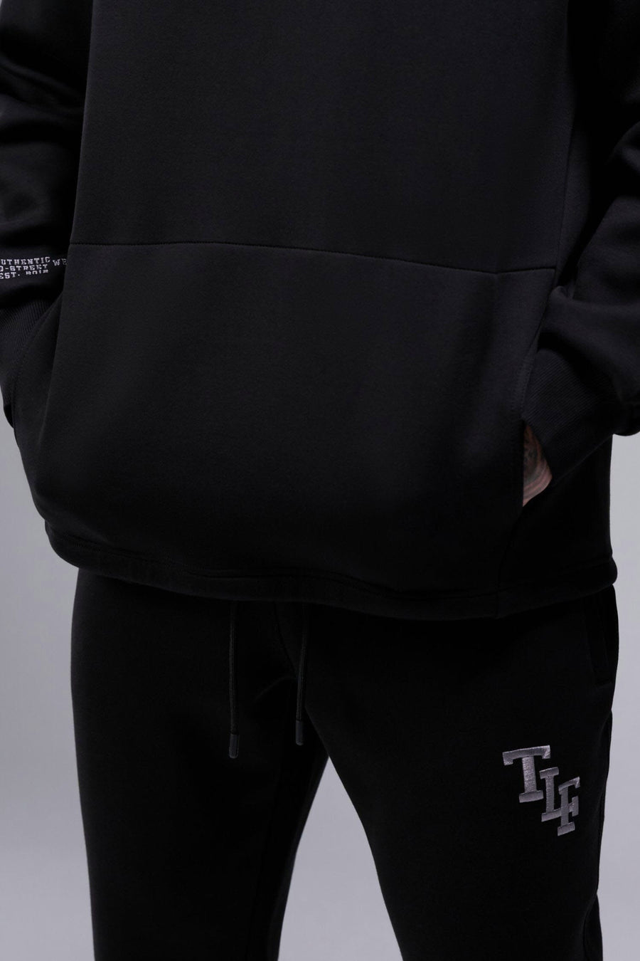 Detail Front View of Black TLF GTS Scuba Tech Quarter-Zip Pullover, featuring a ¼ zip pullover, sleek design and kangaroo pockets