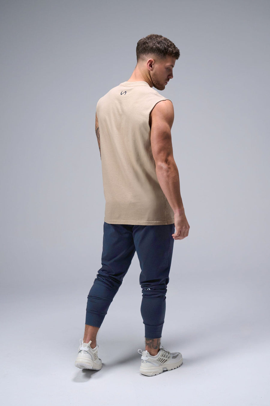 Back View of Tan TLF Property Of Heavy Cotton Muscle Tank featuring a distressed graphic design and raw edge arm holes.