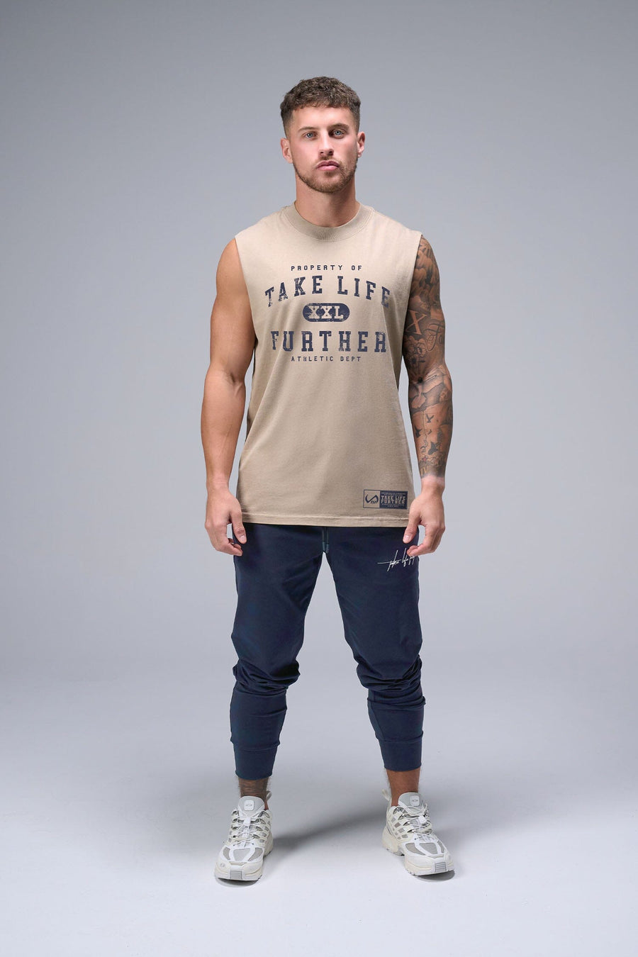 Front View of Tan TLF Property Of Heavy Cotton Muscle Tank featuring a distressed graphic design and raw edge arm holes.