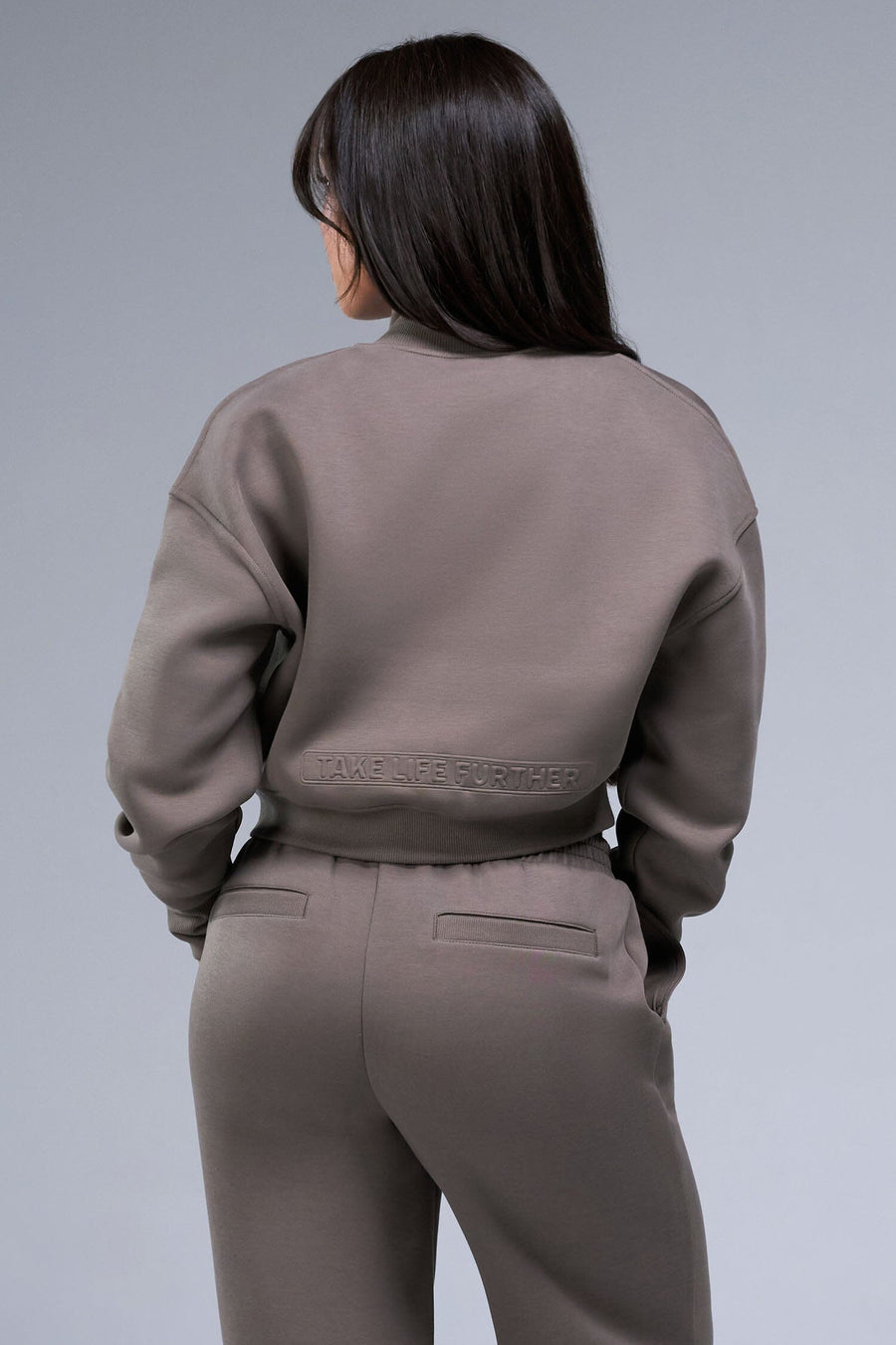 Back View of Brown TLF Scuba Tech Cropped Zip Up Jacket, featuring side zipper pockets, thumbholes and a cropped length