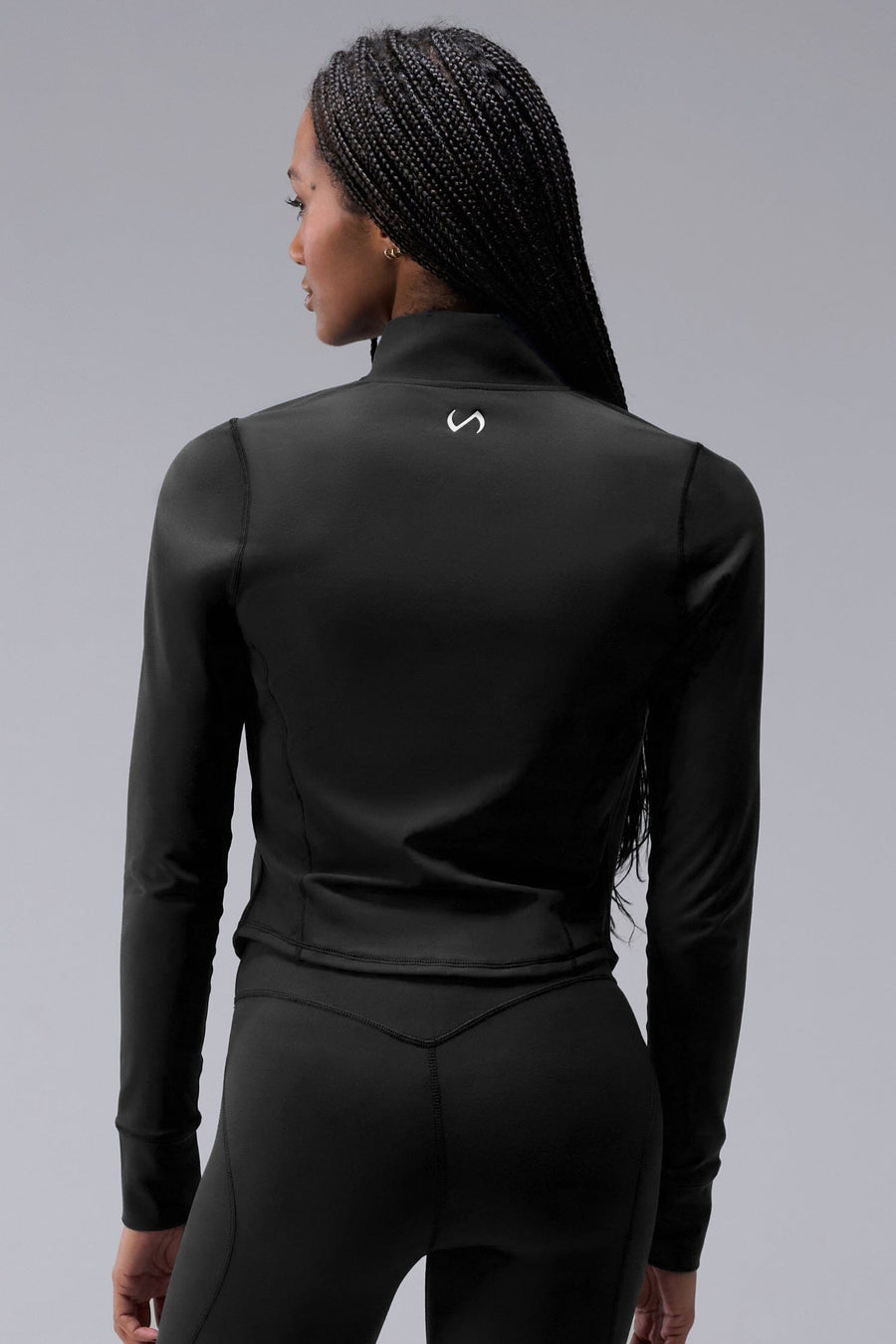 Back View of Black TLF Tempo Cropped Zip Up Jacket featuring thumbholes and cropped length for gym and lifestyle wear