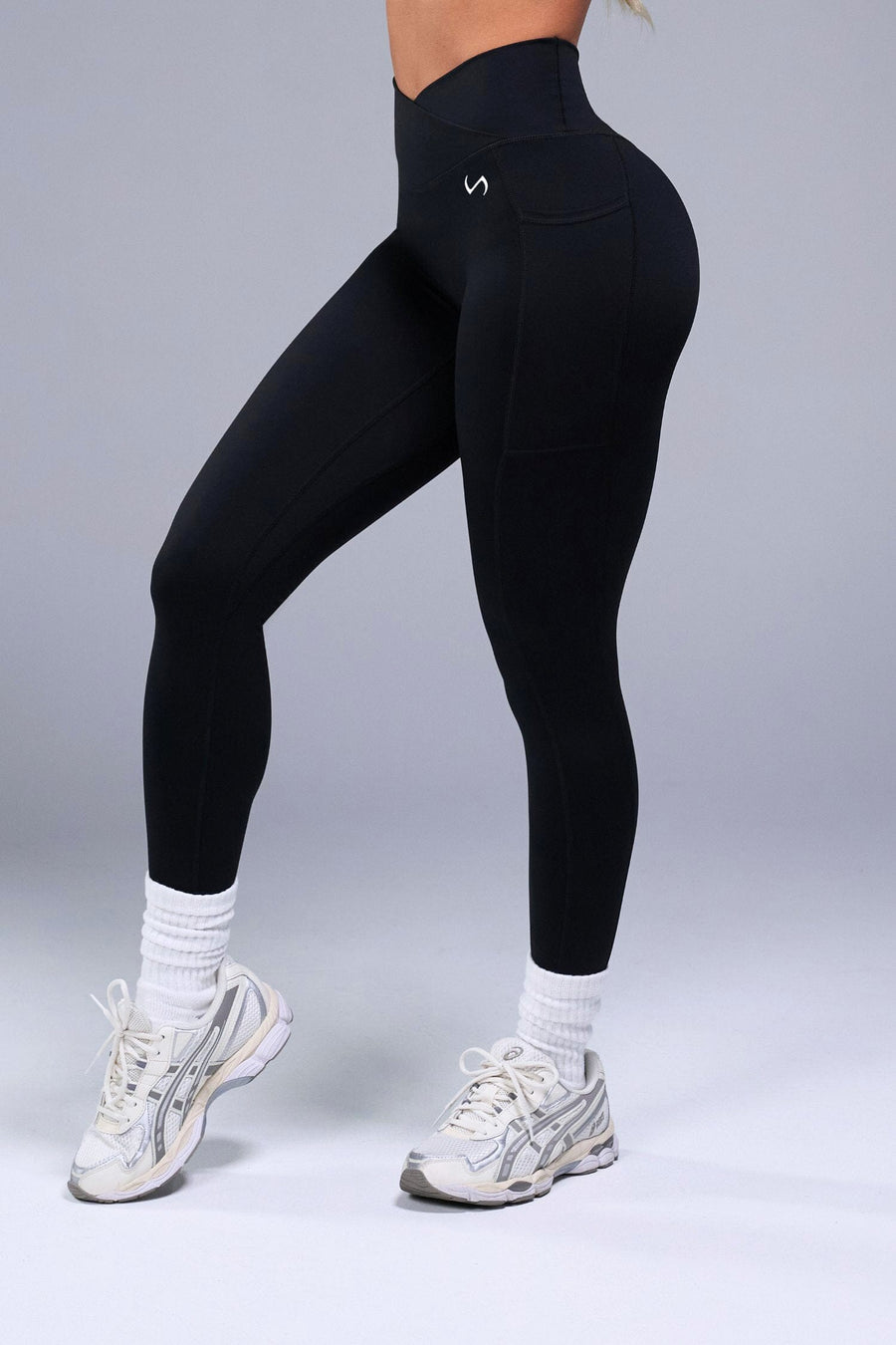 Side View of Black TLF Tempo Side Pocket Leggings, featuring dual side pockets and crossover waistband for performance and functionality