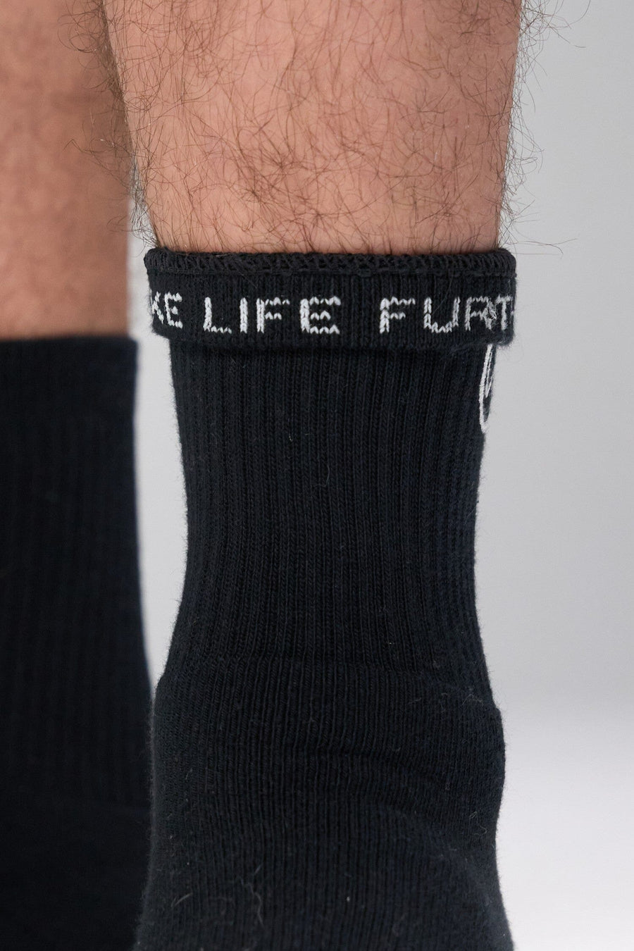Front View of Black the TLF Evolve Half Crew Socks featuring an embroidered TLF logo and interiors take life further stitched detailing with a cushioned footbed