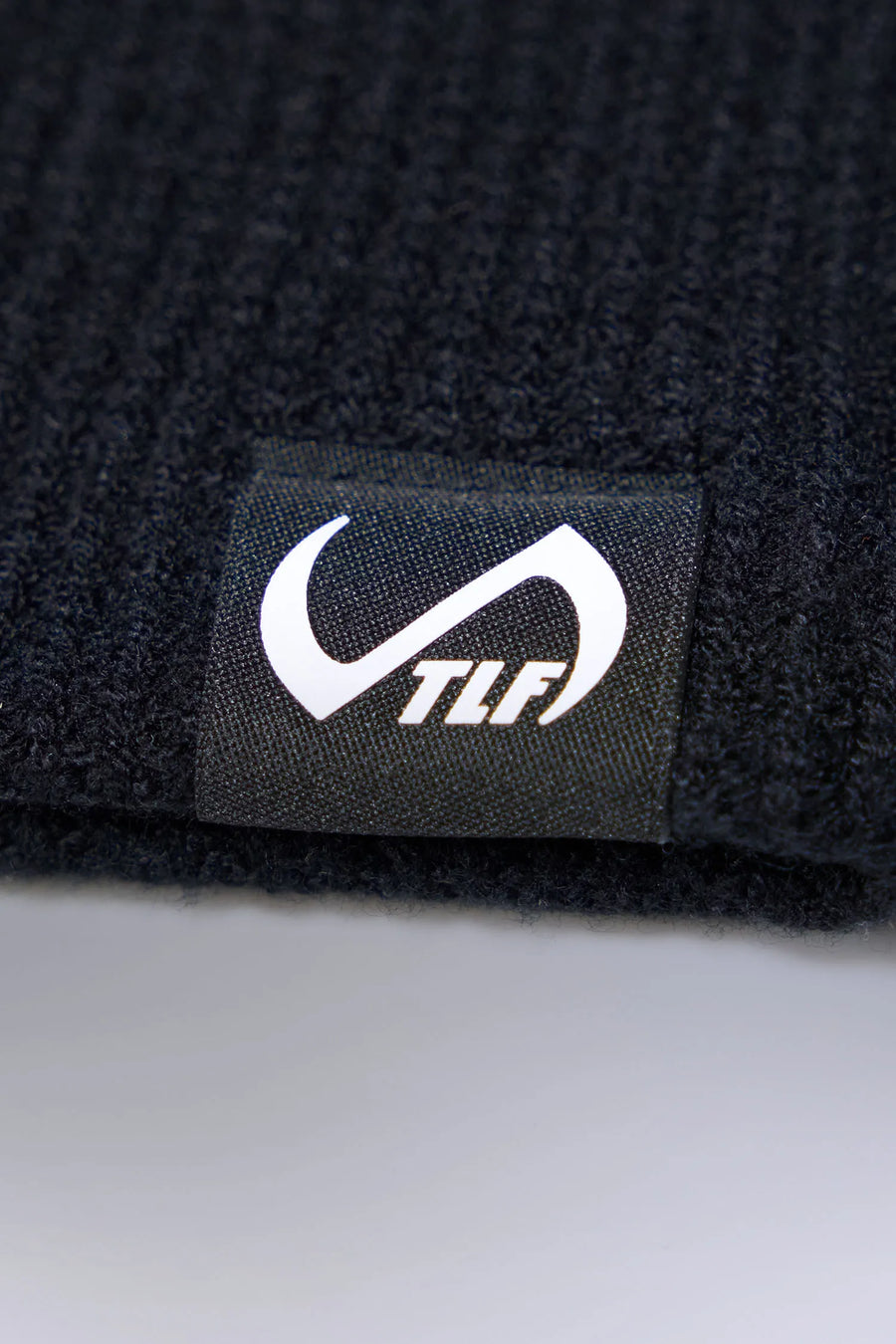Black Unisex Knit Skully Beanie features a TLF clip label and uses a premium viscose knit fabric blend for premium comfort by TLF Apparel – detail view 