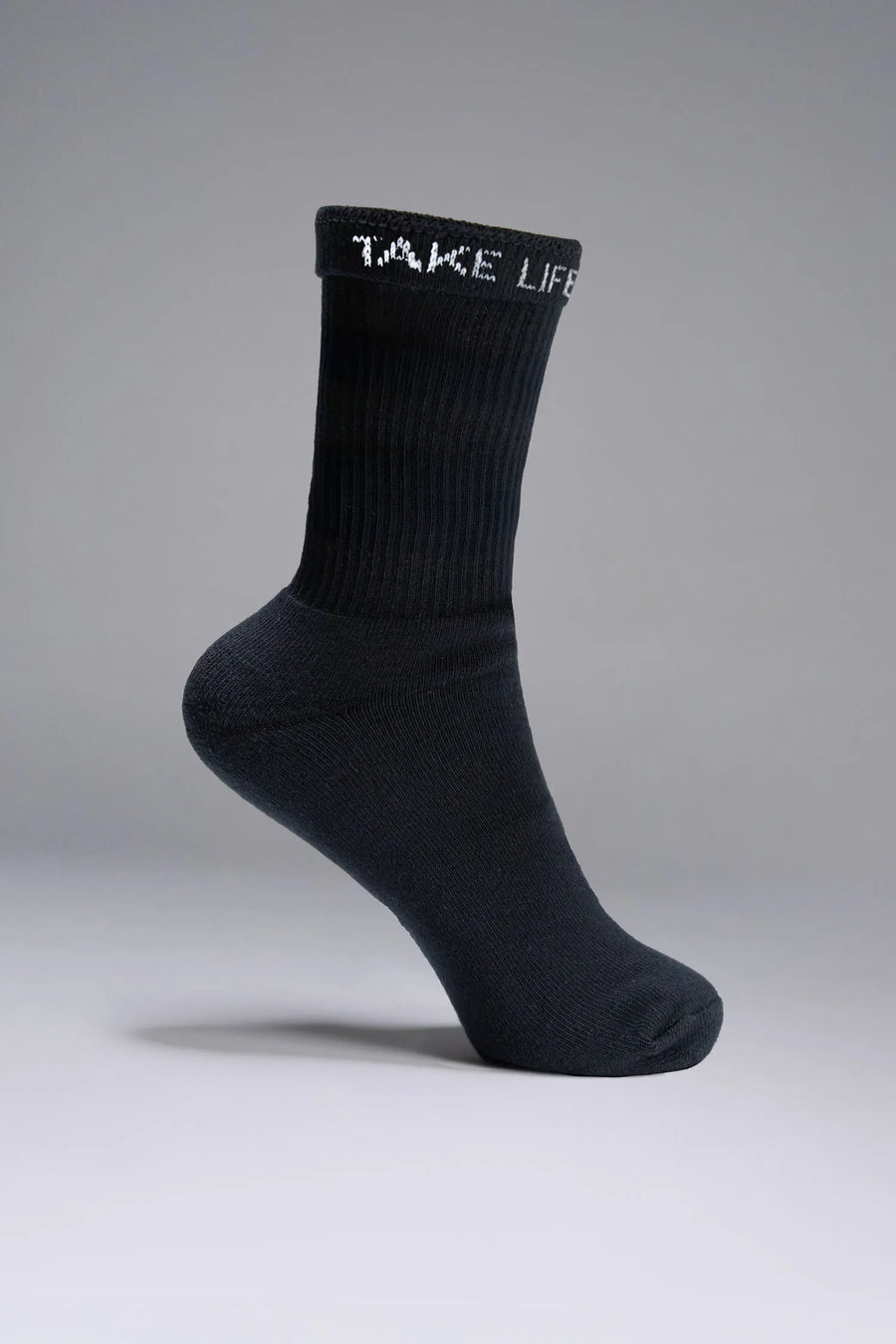 Side View of Black the TLF Evolve Crew Socks featuring an extended cuff height, ribbed cuff, cushioned footbed and seamless toe