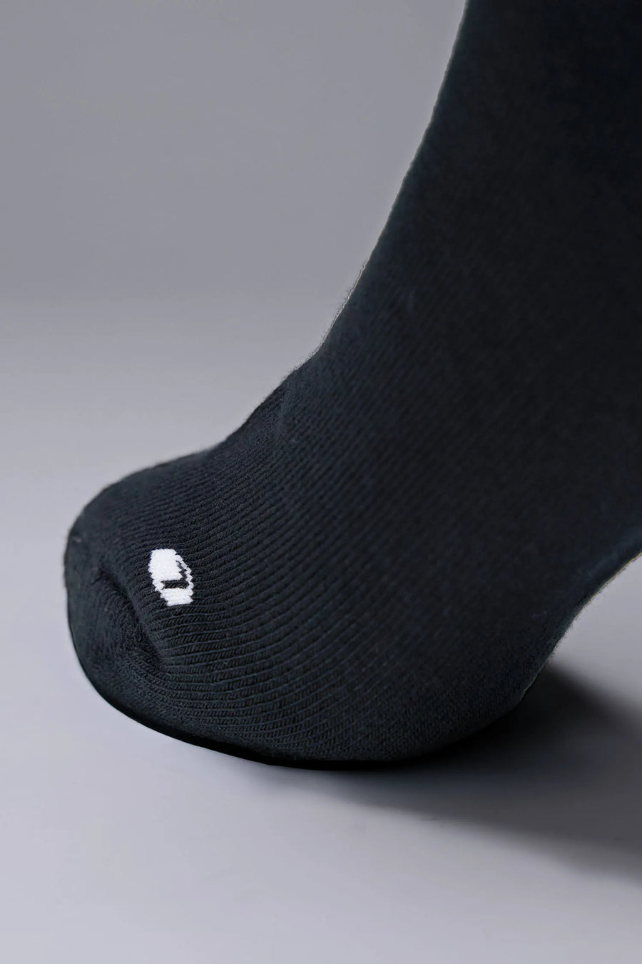 Side View of Black the TLF Evolve Crew Socks featuring an extended cuff height, ribbed cuff, cushioned footbed and seamless toe