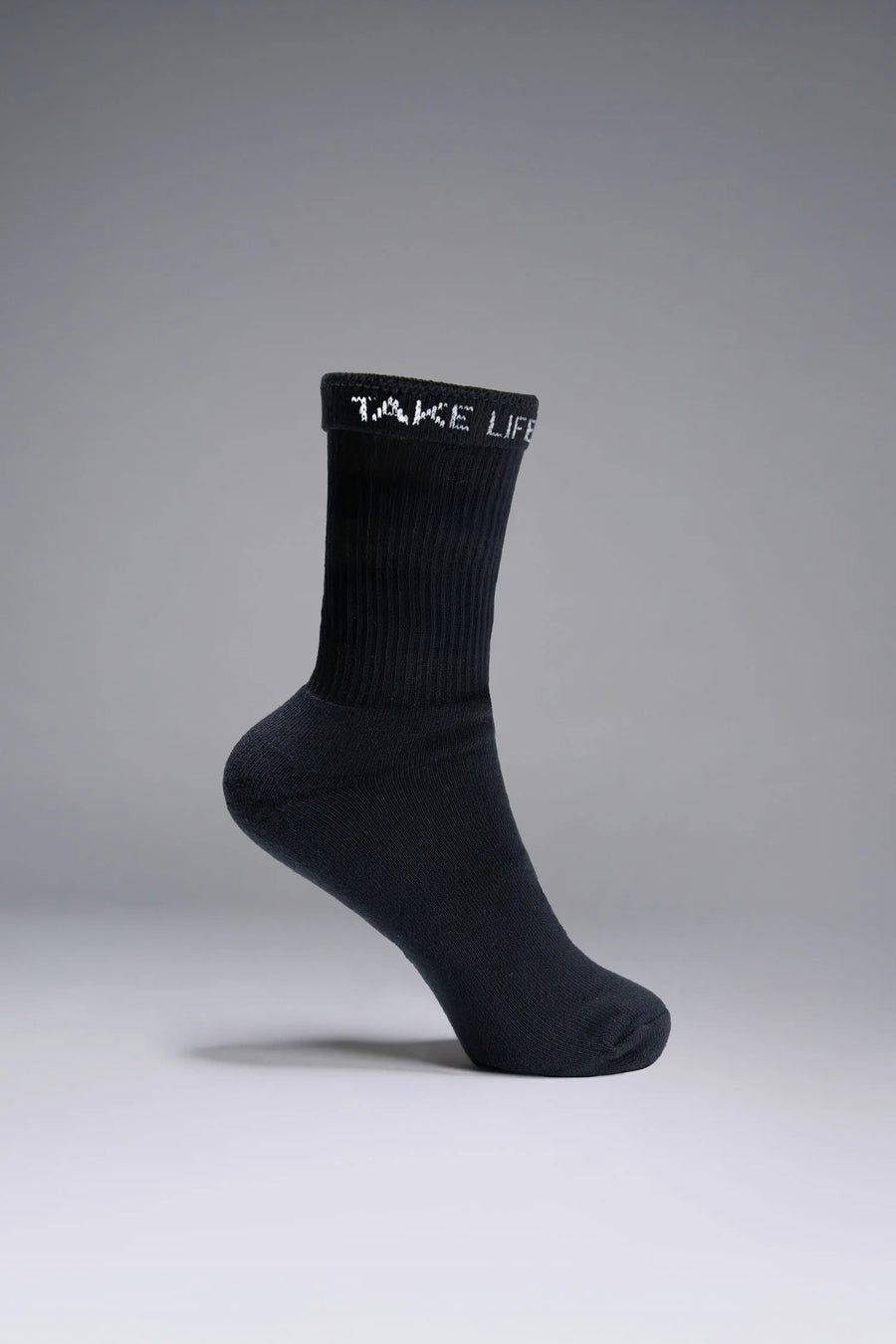 Side View of Black the TLF Evolve Half Crew Socks featuring an extended cuff height, ribbed cuff, cushioned footbed and seamless toe