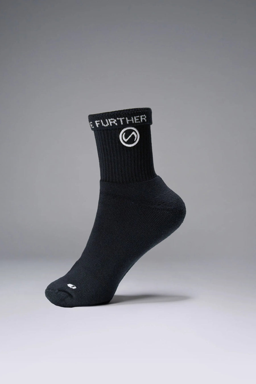 Side View of Black the TLF Evolve Half Crew Socks featuring an extended cuff height, ribbed cuff, cushioned footbed and seamless toe