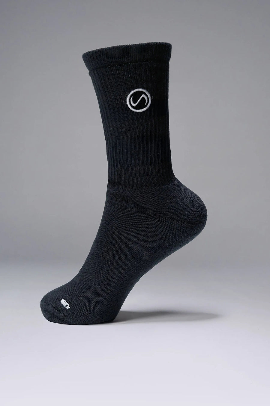 Side View of Black the TLF Evolve Crew Socks featuring an extended cuff height, ribbed cuff, cushioned footbed and seamless toe