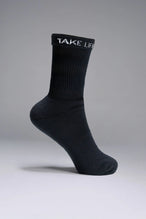 Side View of Black the TLF Evolve Crew Socks featuring an extended cuff height, ribbed cuff, cushioned footbed and seamless toe
