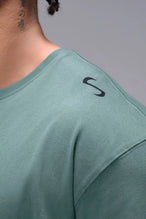 Green Classic Script Cotton Luxe Oversized Tee showing left neck icon logo, woven hem clip label, and Cotton Luxe DNA fabric by TLF Apparel – detail view 