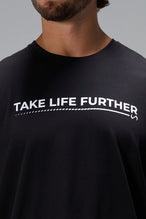 Black Take Life Further Oversized Tee showing side split hem, woven hem clip label, and Cotton Luxe DNA fabric by TLF Apparel – detail view 