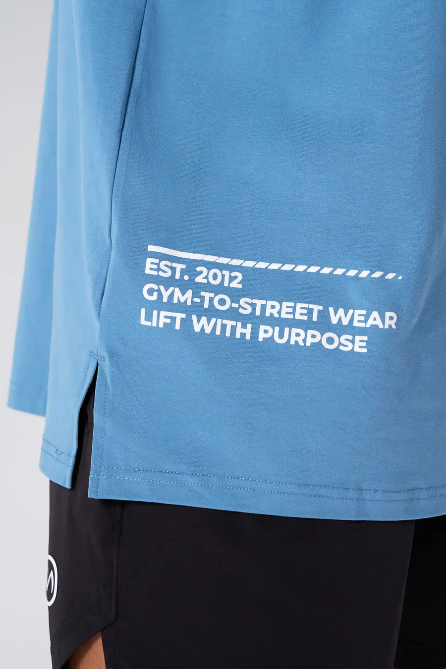 Blue Take Life Further Oversized Tee showing side split hem, woven hem clip label, and Cotton Luxe DNA fabric by TLF Apparel – detail view