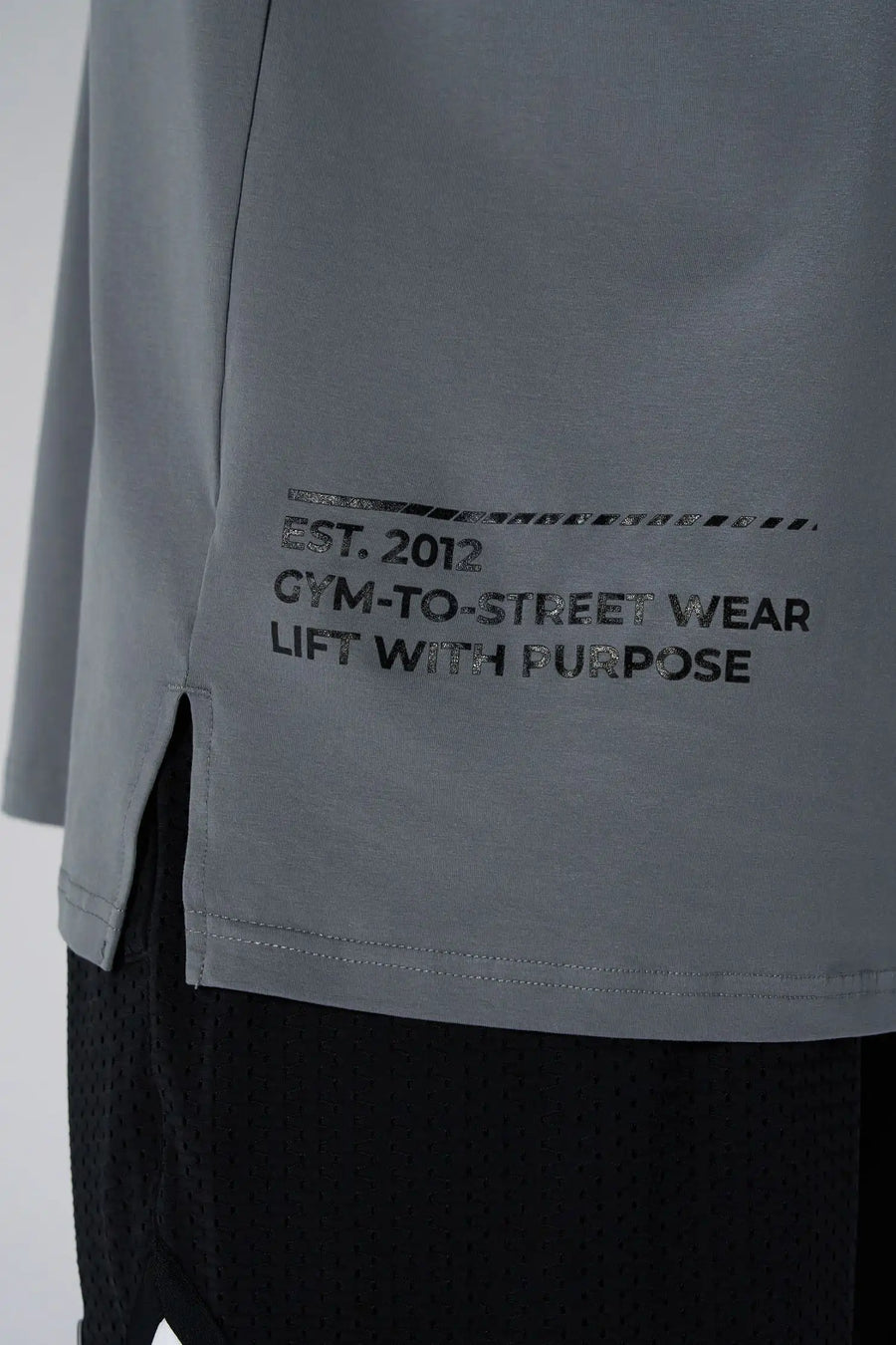 Gray Take Life Further Oversized Tee showing side split hem, woven hem clip label, and Cotton Luxe DNA fabric by TLF Apparel – detail view 
