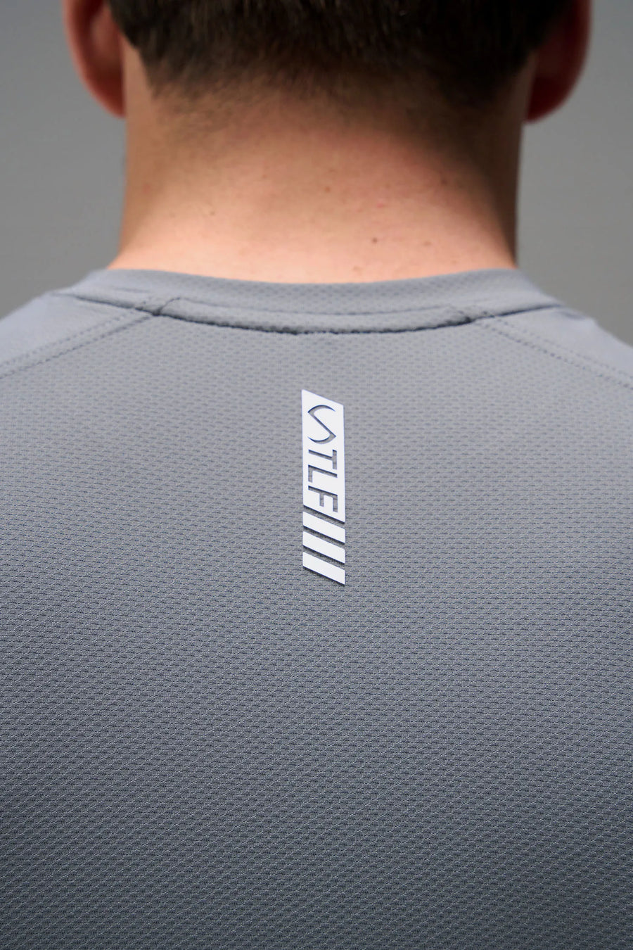 Gray Men’s Micro Mesh Tee with a physique-enhancing fit, designed for gym training, HIIT workouts and running by TLF Apparel – back view 