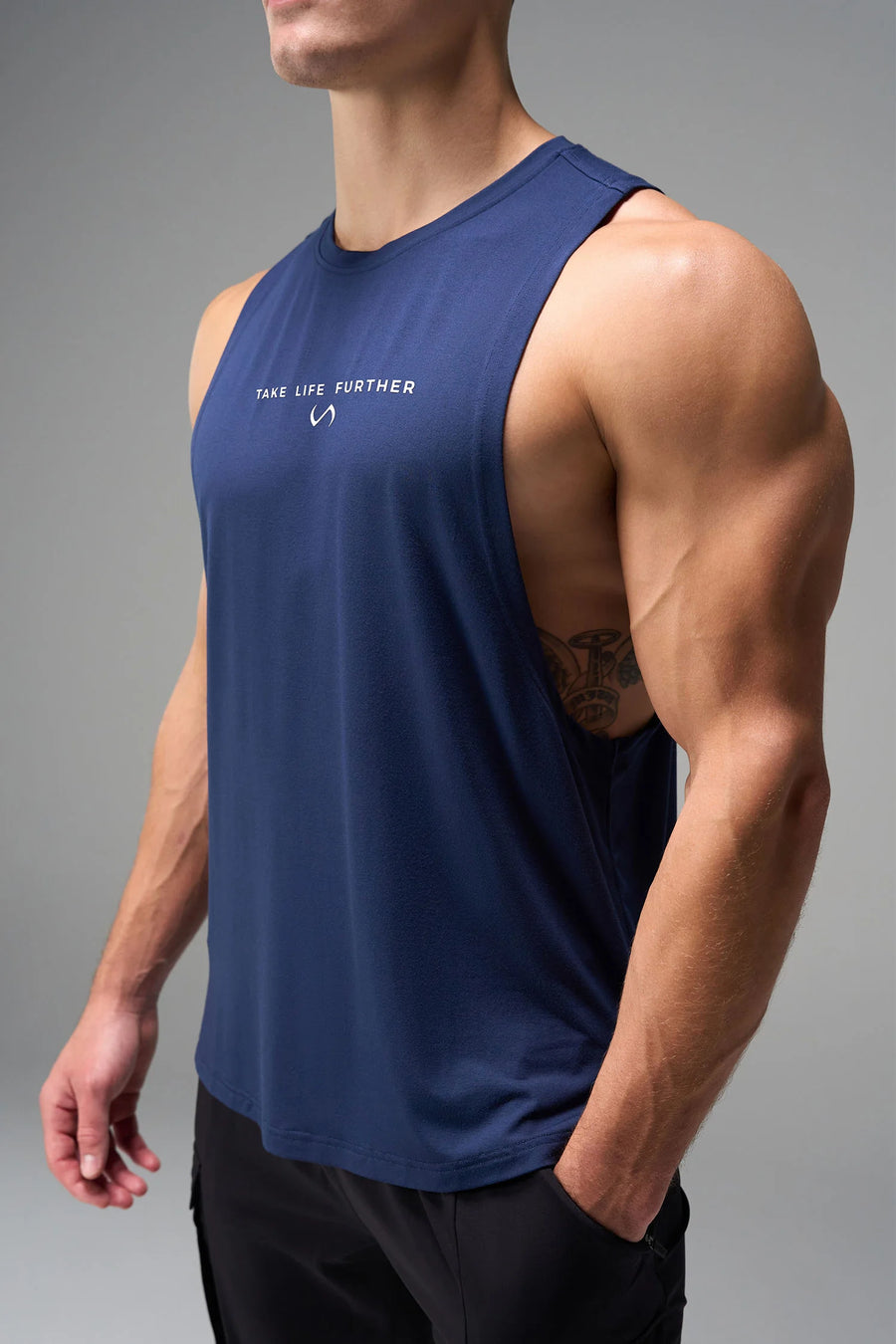 Blue Further Air-Flex Drop Arm Tank showing ultra-soft performance fabric and Take Life Further® chest logo detail by TLF Apparel – detail view