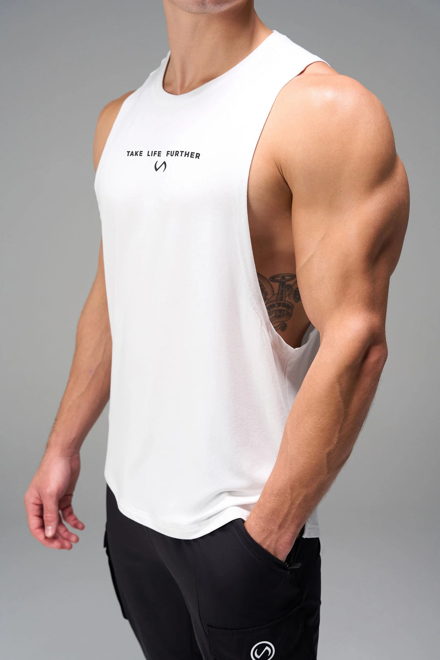 White Further Air-Flex Drop Arm Tank showing ultra-soft performance fabric and Take Life Further® chest logo detail by TLF Apparel – detail view