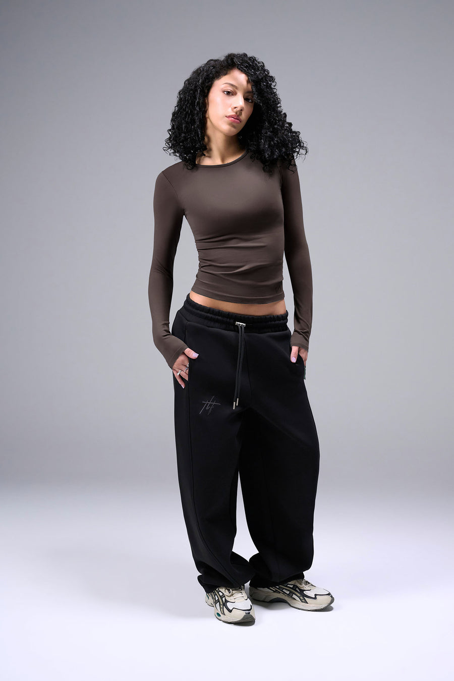 Women’s dark oak essential seamless long sleeve top with contouring fit for gym and lifestyle by TLF Apparel – full body hands in pocket front view