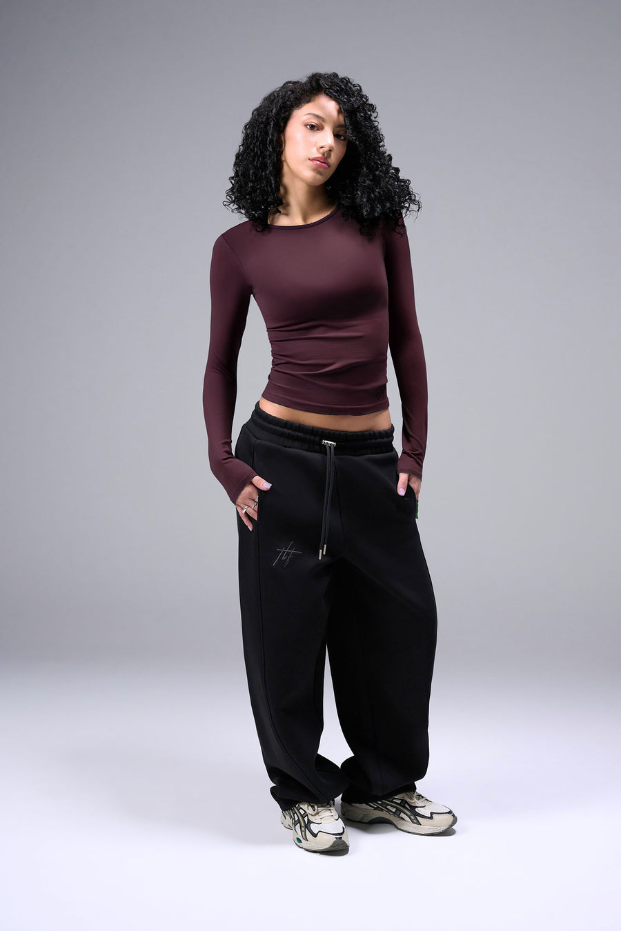 Women’s wine essential seamless long sleeve top with contouring fit for gym and lifestyle by TLF Apparel – full body hands in pocket front view