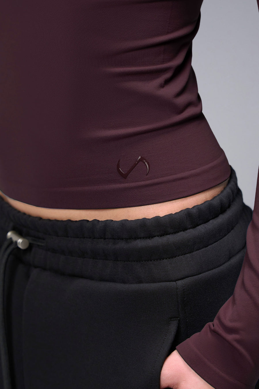 Women’s wine essential seamless long sleeve top with contouring fit for gym and lifestyle by TLF Apparel – detail logo view
