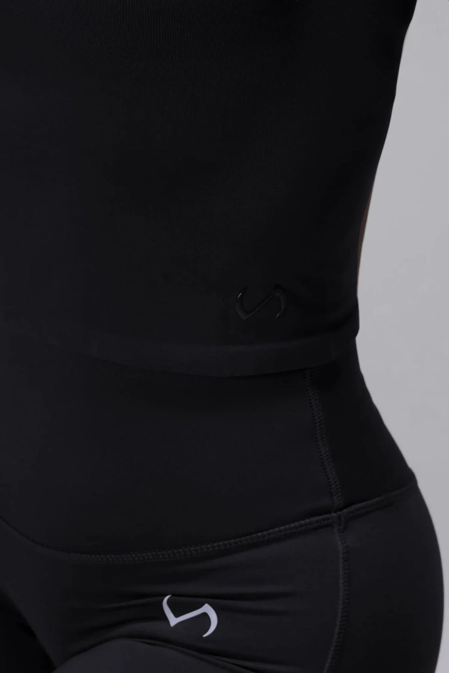 Detail Side View of Black TLF Essential Seamless Mock Neck Long Sleeve, featuring thumbholes and mock neck for gym to street versatility