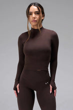 Front View of Brown TLF Essential Seamless Mock Neck Long Sleeve, featuring thumbholes and mock neck for gym to street versatility