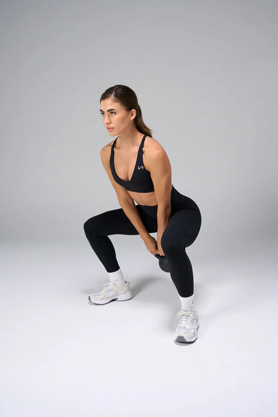 Black NeoCloud™ V-Neck Sports Bra with v neckline and medium support for the studio classes, pilates and gym training by TLF Apparel – front view 