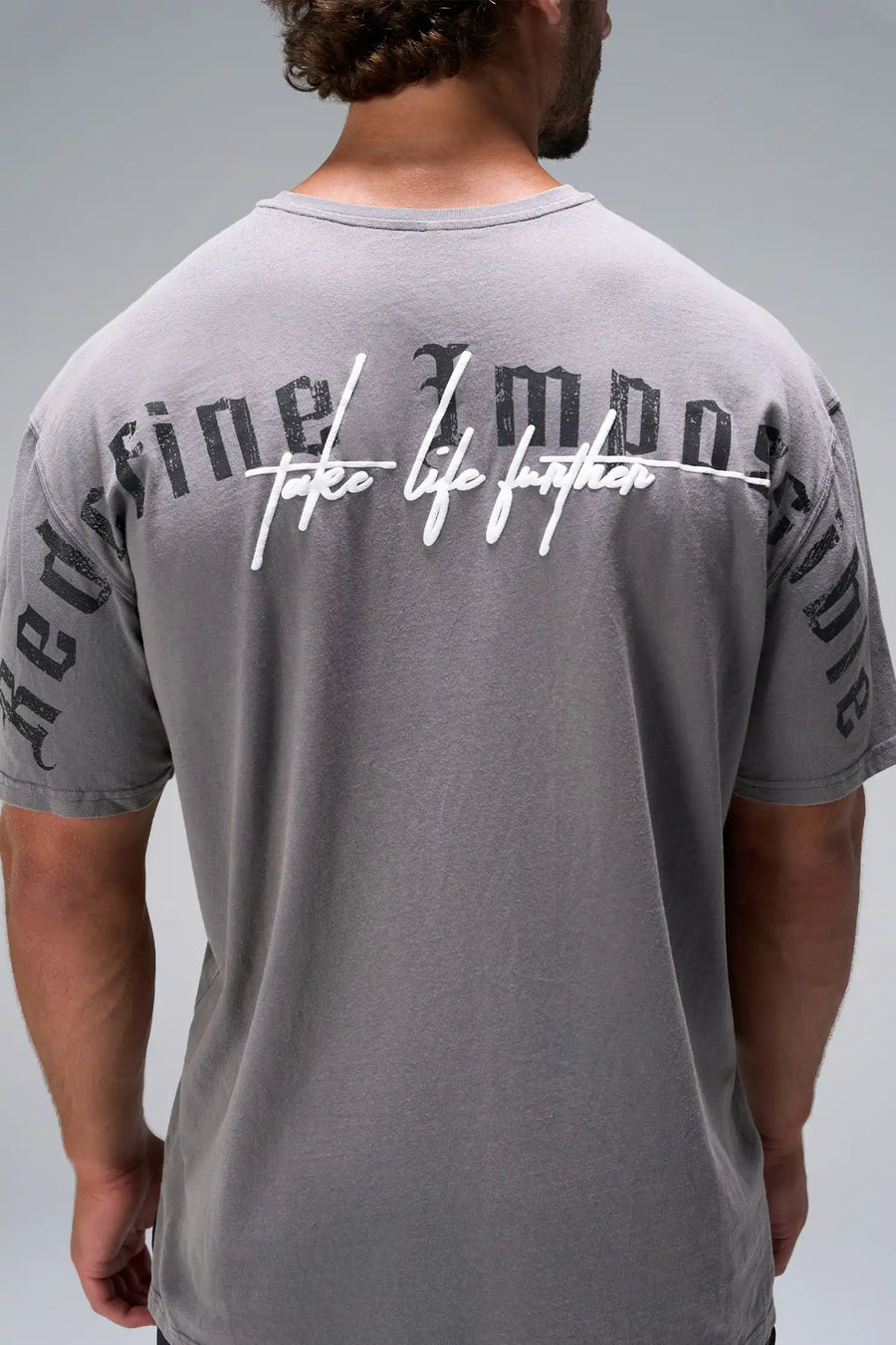 Gray RI Oversized Dura Cotton Short Sleeve Tee showing puff print Take Life Further script, stonewash finish, and woven hem clip label by TLF Apparel – detail view