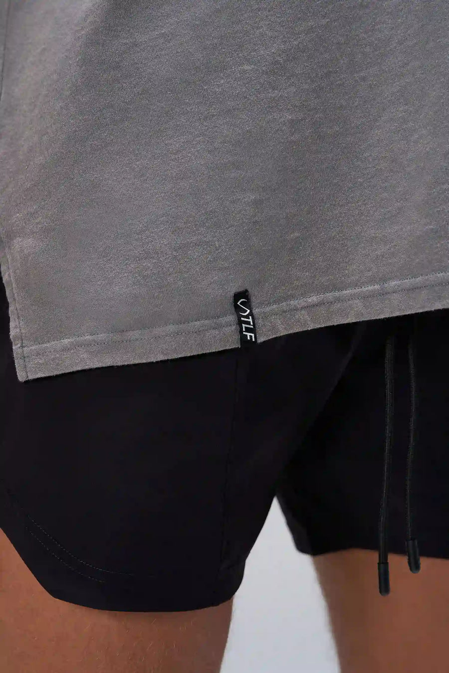 Gray RI Oversized Dura Cotton Short Sleeve Tee showing stonewash finish, and woven hem clip label by TLF Apparel – detail view