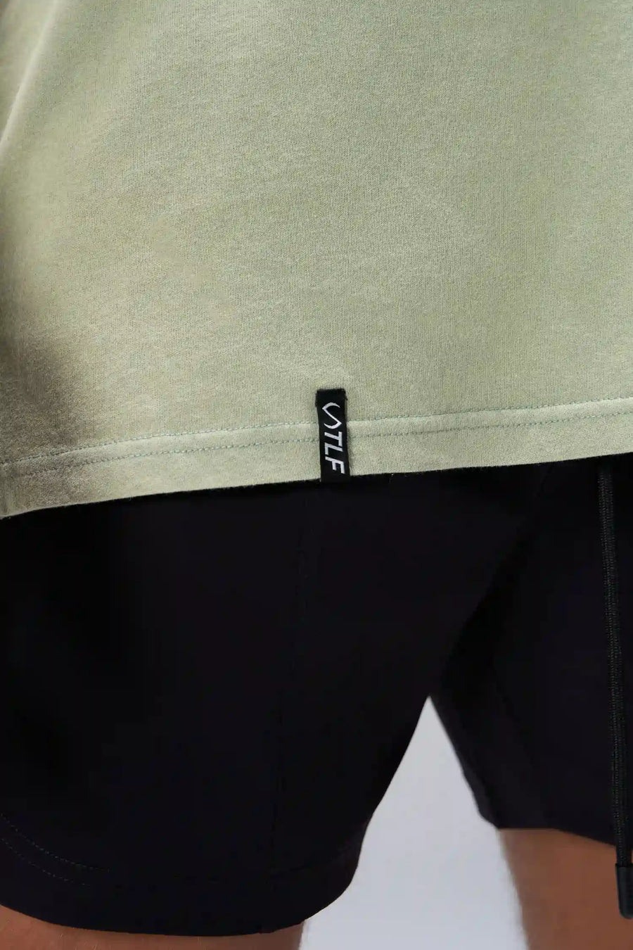Green RI Oversized Dura Cotton Short Sleeve Tee showing stonewash finish, and woven hem clip label by TLF Apparel – detail view