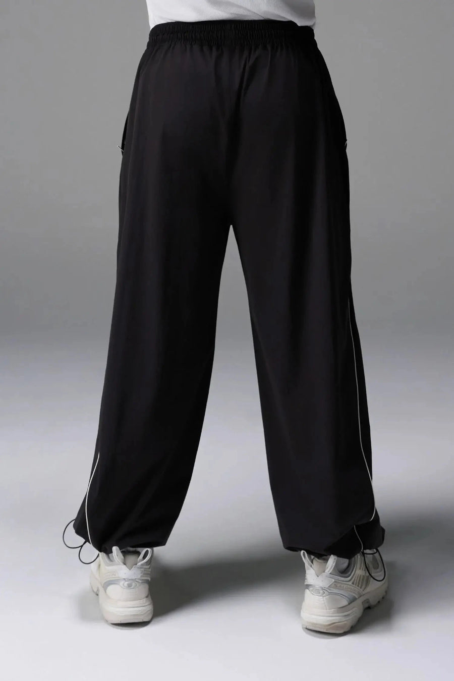 Back View of Black TLF Baggy Track Pants (Men’s GTS Gym-To-Street Edition) featuring side pockets and reflective piping details with an oversized fit 