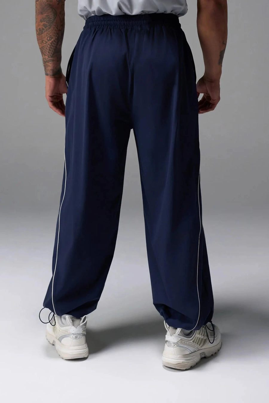 Back View of Blue TLF Baggy Track Pants (Men’s GTS Gym-To-Street Edition) featuring side pockets and reflective piping details with an oversized fit 