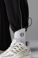 Detail Front View of Black TLF Baggy Track Pants (Men’s GTS Gym-To-Street Edition) featuring side pockets and reflective piping details with an oversized fit 