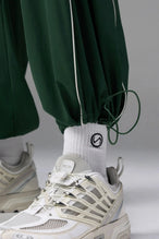 Detail Front View of Green TLF Baggy Track Pants (Men’s GTS Gym-To-Street Edition) featuring side pockets and reflective piping details with an oversized fit 