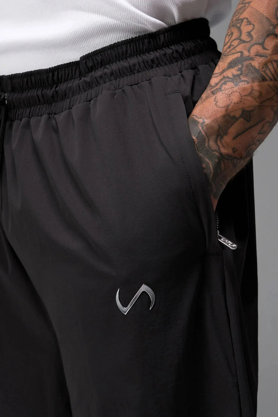 Detail View of Black TLF Baggy Track Pants (Men’s GTS Gym-To-Street Edition) featuring side pockets and reflective piping details with an oversized fit 