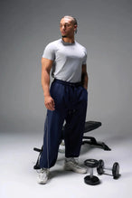 Front View of Blue TLF Baggy Track Pants (Men’s GTS Gym-To-Street Edition) featuring side pockets and reflective piping details with an oversized fit 