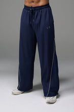 Front View of Blue TLF Baggy Track Pants (Men’s GTS Gym-To-Street Edition) featuring side pockets and reflective piping details with an oversized fit 