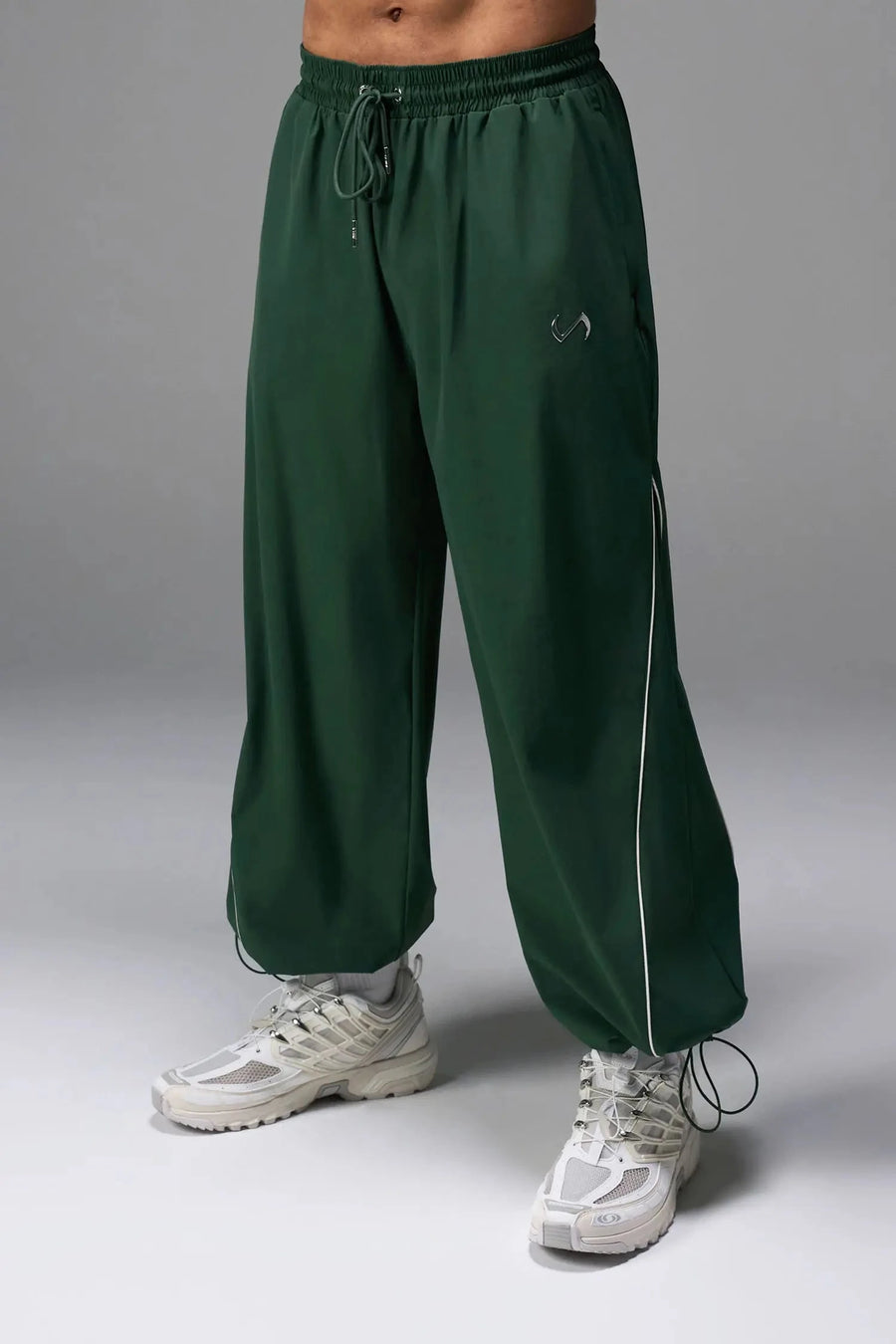 Front View of Green TLF Baggy Track Pants (Men’s GTS Gym-To-Street Edition) featuring side pockets and reflective piping details with an oversized fit 