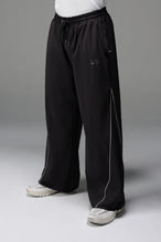 Front View of Black TLF Baggy Track Pants (Men’s GTS Gym-To-Street Edition) featuring side pockets and reflective piping details with an oversized fit 