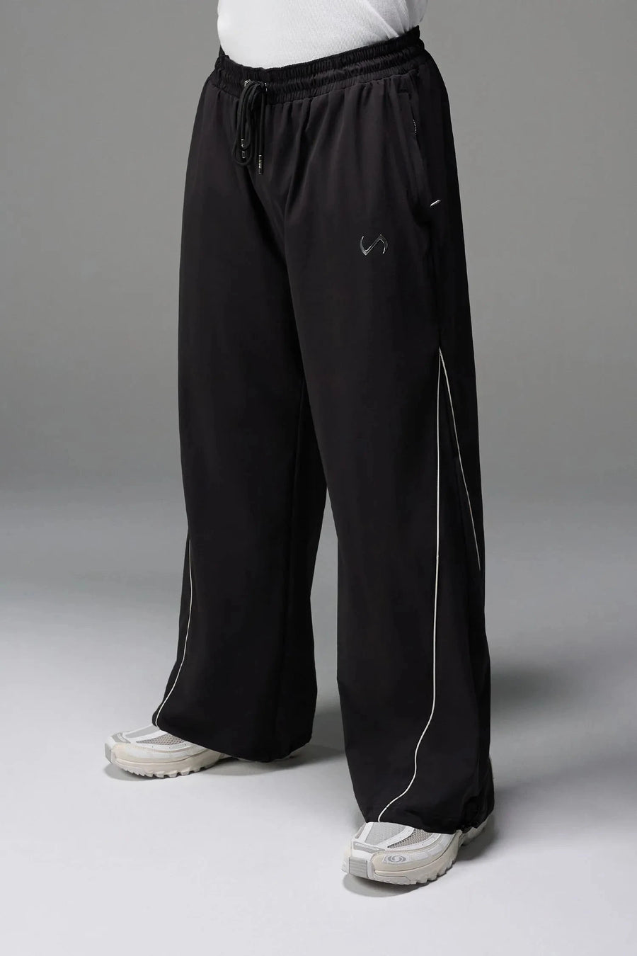 Front View of Black TLF Baggy Track Pants (Men’s GTS Gym-To-Street Edition) featuring side pockets and reflective piping details with an oversized fit 