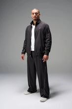 Front View of Black TLF Baggy Track Pants (Men’s GTS Gym-To-Street Edition) featuring side pockets and reflective piping details with an oversized fit 