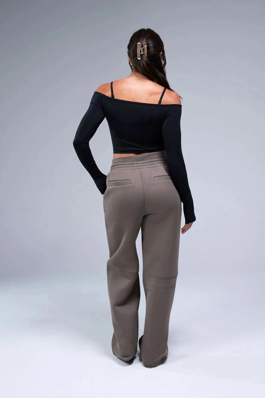 Back View of Black TLF Essential Seamless off the shoulder top, featuring a cropped length and thumbholes 