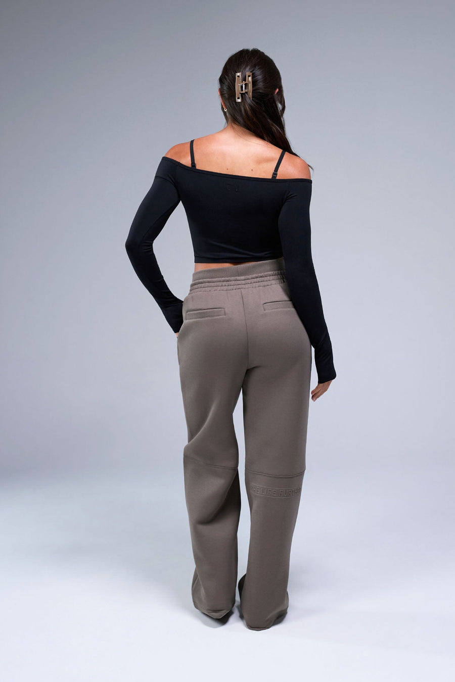 Back View of Black TLF Essential Seamless off the shoulder top, featuring a cropped length and thumbholes 