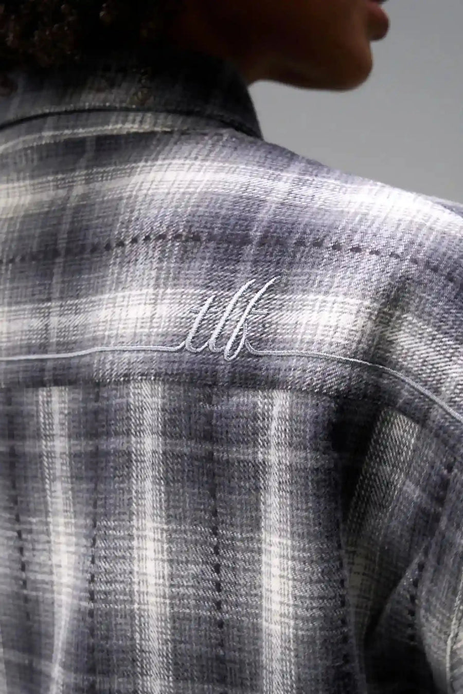 Back Detail View of the Black TLF Flannel Shacket featuring premium embroidery details on the collar and back in a cotton plaid flannel fabric