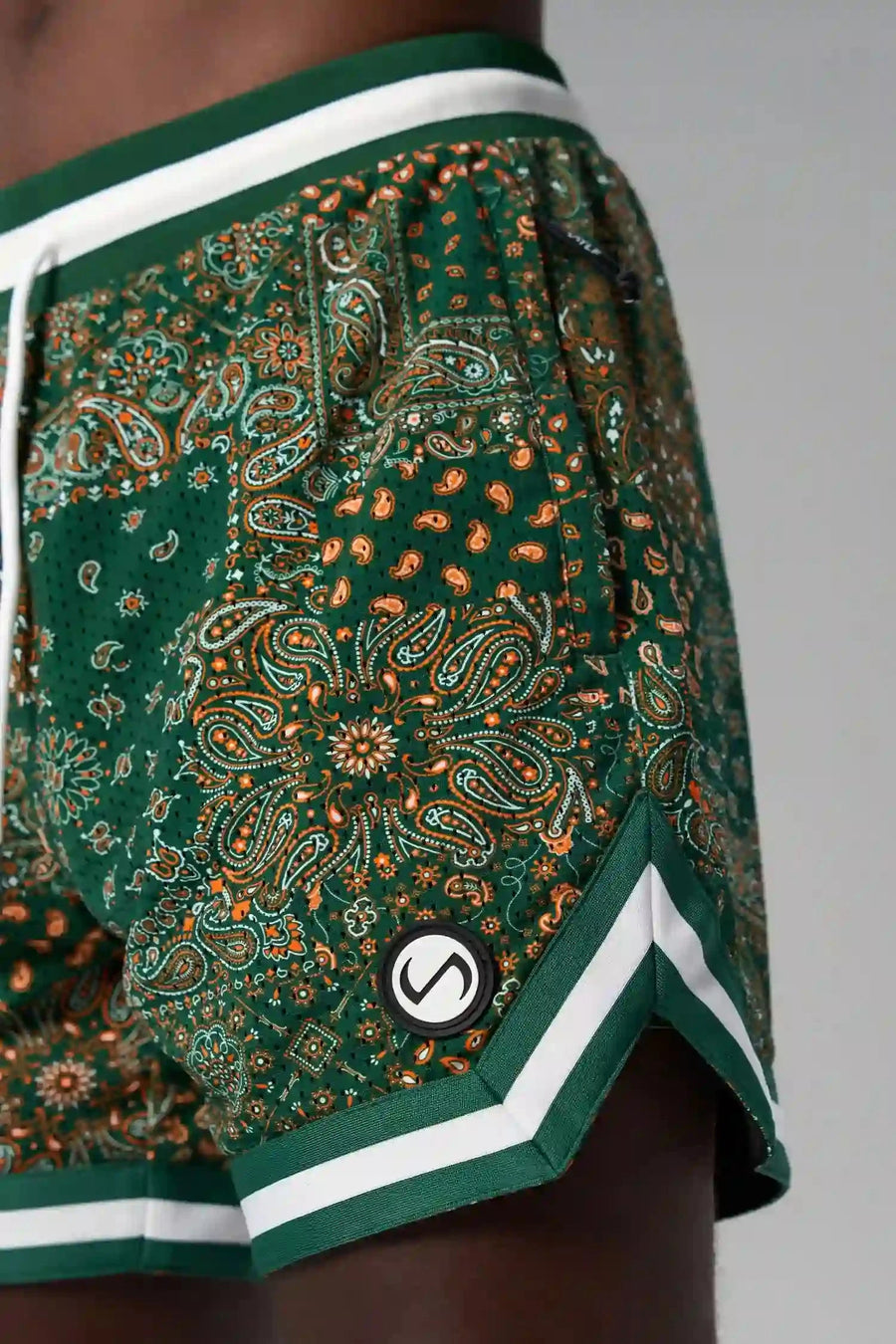 Detail Front View of Green GTS Evolve Mesh 6 Inch Shorts, featuring university of Miami inspired patch paisley design and zipper pockets