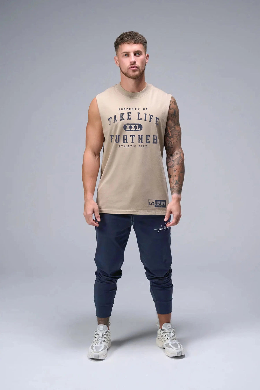 Front View of Tan TLF Property Of Heavy Cotton Muscle Tank featuring a distressed graphic design and raw edge arm holes. 