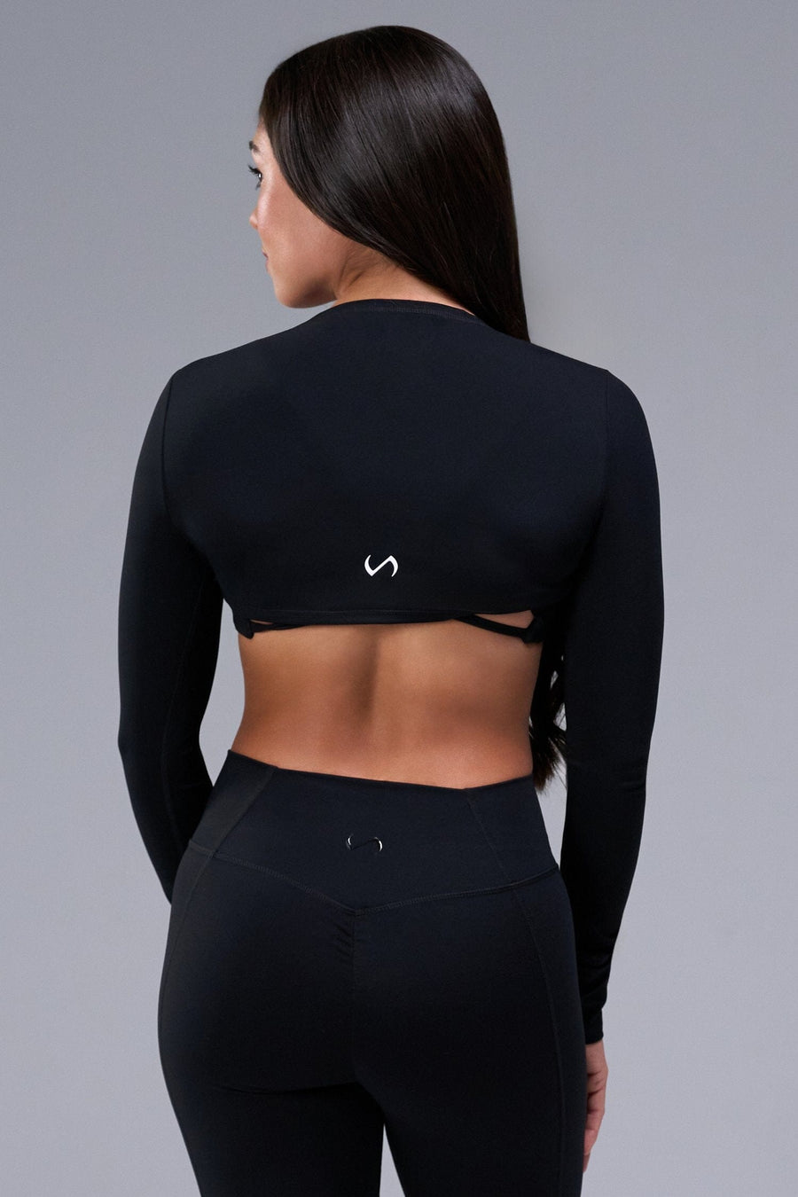 Back View of Black Tempo Bolero Shrug featuring thumbholes, designed for workouts and all day wear 