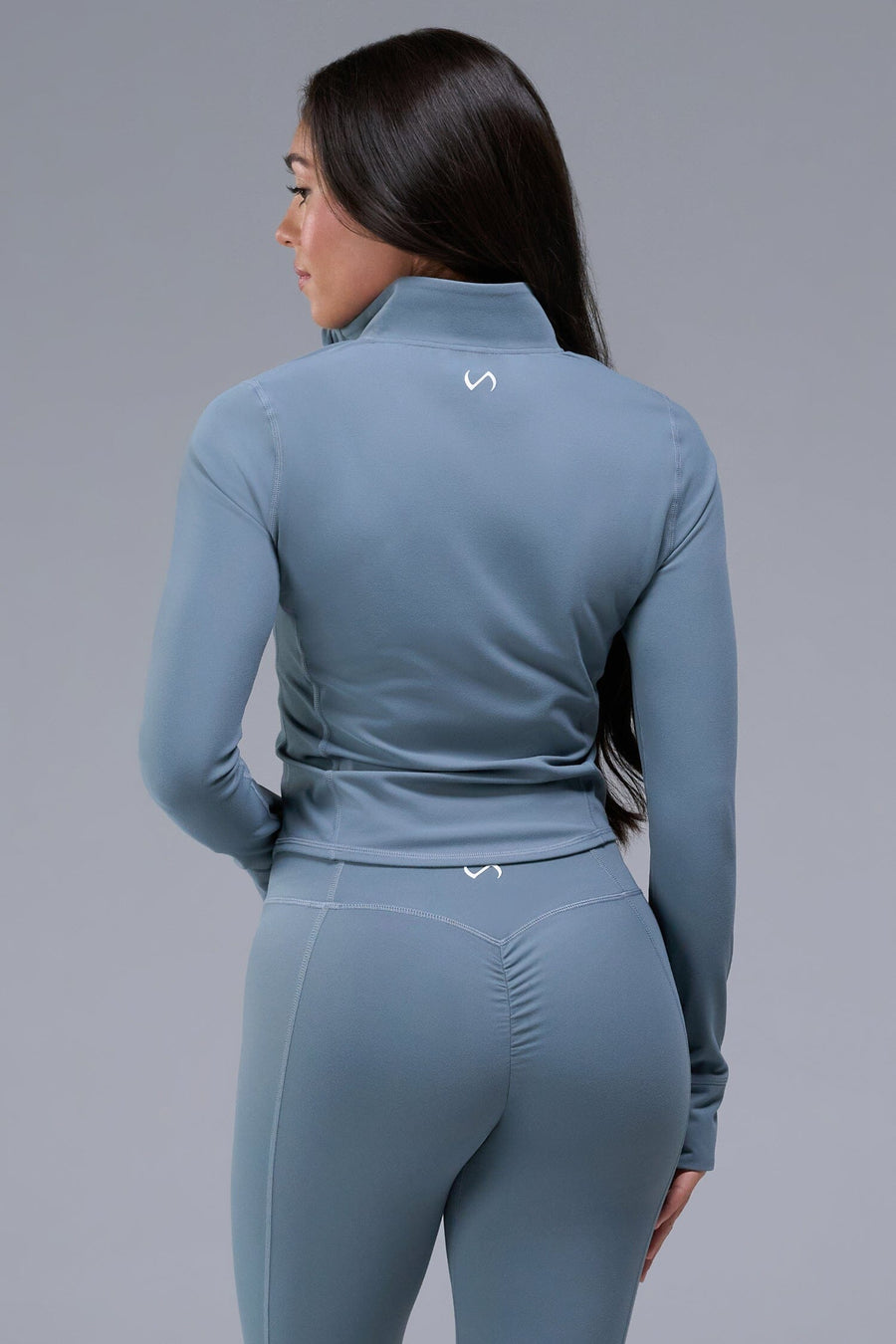 Back View of Blue TLF Tempo Cropped Zip Up Jacket featuring thumbholes and cropped length for gym and lifestyle wear 